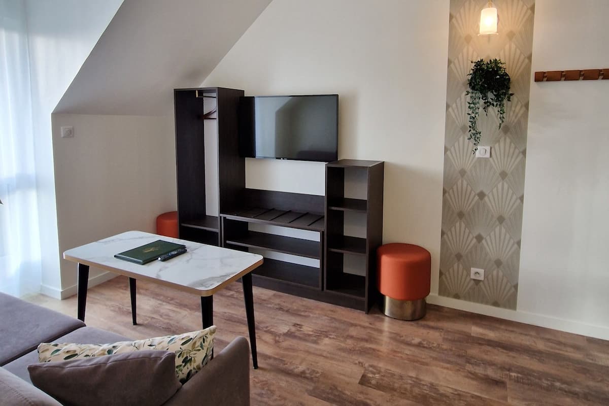 A modern living room with a flat-screen TV, a sofa, a coffee table, and a wooden floor.