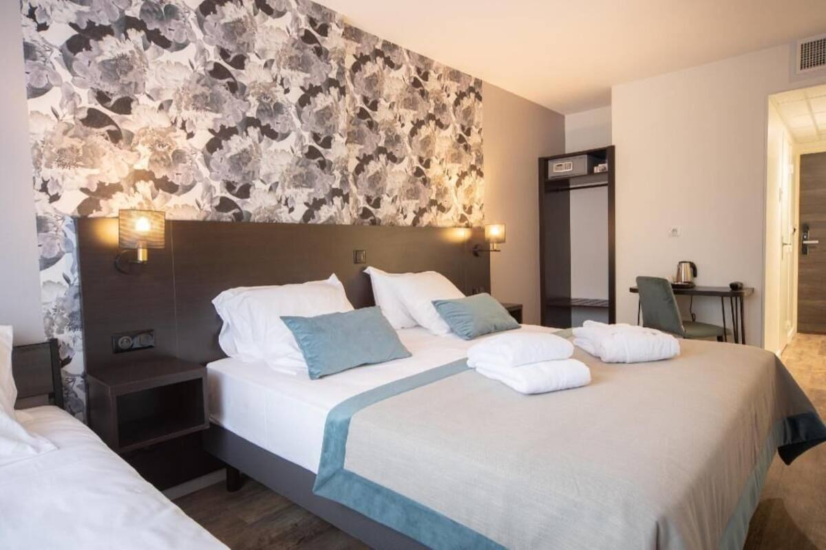 A hotel room with a large bed, two bedside tables, a desk, and a chair.