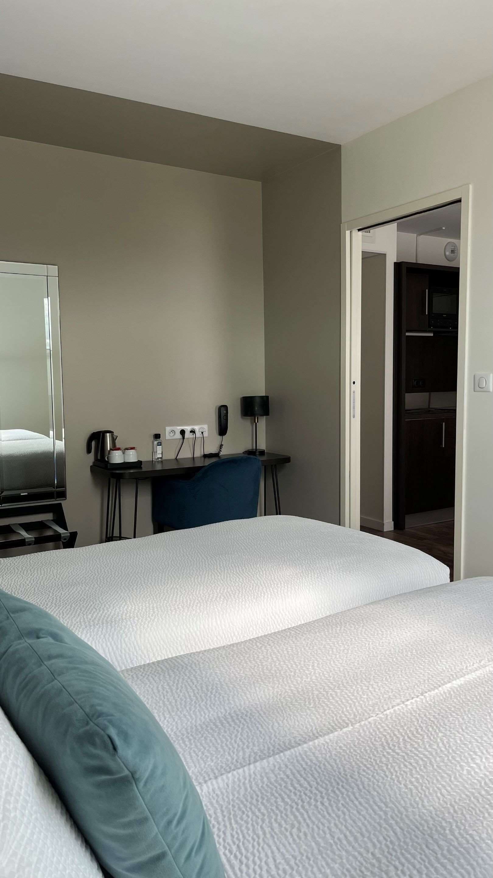 A hotel room with a bed, a desk, a chair, a coffee maker, a phone, and a microwave.