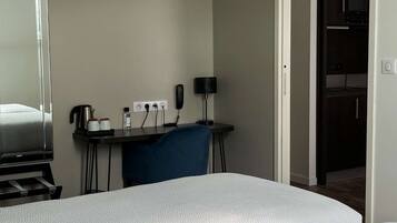 A hotel room with a bed, a desk, a chair, a coffee maker, a phone, and a microwave.