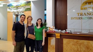 A reception area with a marble reception desk, a wall-mounted sign reading "TRANG INTERNATIONAL", and a decorative plant on the desk. - Trang An International Hotel (Tay Hoa Lu)