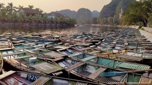 A riverfront with numerous boats docked along the shore. - Trang An International Hotel (Tay Hoa Lu)