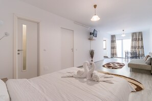 Una habitación de hotel con cama, televisor, sofá y zona de comedor.