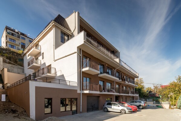 A multi-story residential building with balconies, a garage, and parked cars. - Nicobri Studios (Floresti)