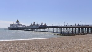 A pier extending into the sea with a building featuring domed roofs at the end.