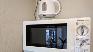 Un four à micro-ondes blanc doté d’un écran numérique et d’une molette de réglage de la puissance, posé sur un plan de travail de couleur beige.