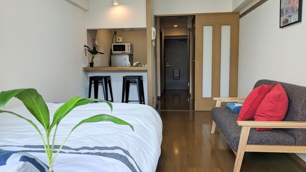 Une chambre d’hôtel avec un lit, une petite kitchenette, un canapé et un plancher en bois.
