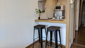 Une petite cuisine équipée d’un four à micro-ondes, d’un évier et de deux tabourets.