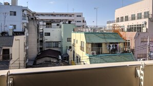 Un immeuble résidentiel à plusieurs étages, doté de balcons, de climatiseurs et d’un petit espace buanderie visible au rez-de-chaussée.