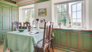 A dining area with a table set for two, a chair, a bowl, a bottle, and a vase with flowers. - Cozy apartment in Sydals (Sydals)