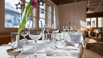 A dining table set with clear glassware, a silver bowl, and a vase with a single flower.