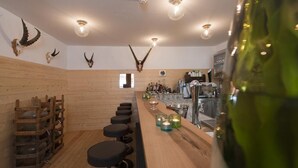 A bar area with wooden walls, mounted animal skulls, and a bar counter with stools. - Hotel Restaurant Capricorns (Muntogna da Schons)