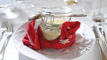 Un bocal en verre doté d’un couvercle métallique à fermoir, contenant une substance crémeuse, posé sur une assiette blanche avec une serviette en tissu rouge.