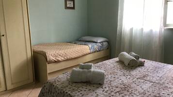 A room with a bed, a table with towels, and a door.