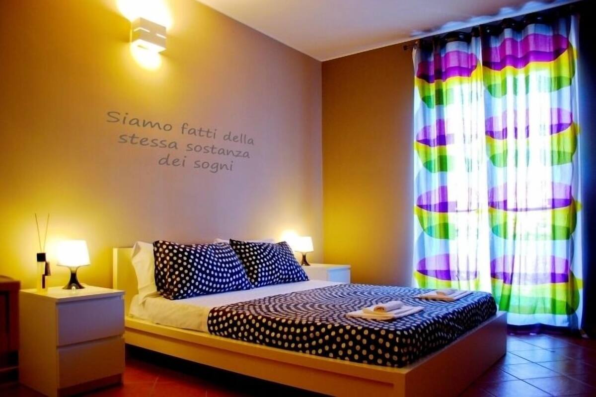 A bedroom with a bed, two bedside tables, and a wall with a motivational quote.