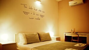 A hotel room with a bed, bedside tables, a desk, and an air conditioning unit. - B&B Charming House (Barletta)