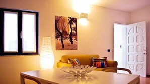 A living room with a sofa, a table with a decorative bowl, a wall-mounted light, and a door. - B&B Charming House (Barletta)