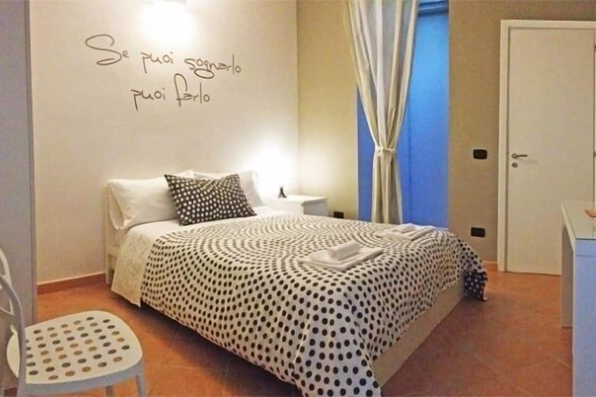 A bedroom with a bed, a chair, a desk, and a wall with text.