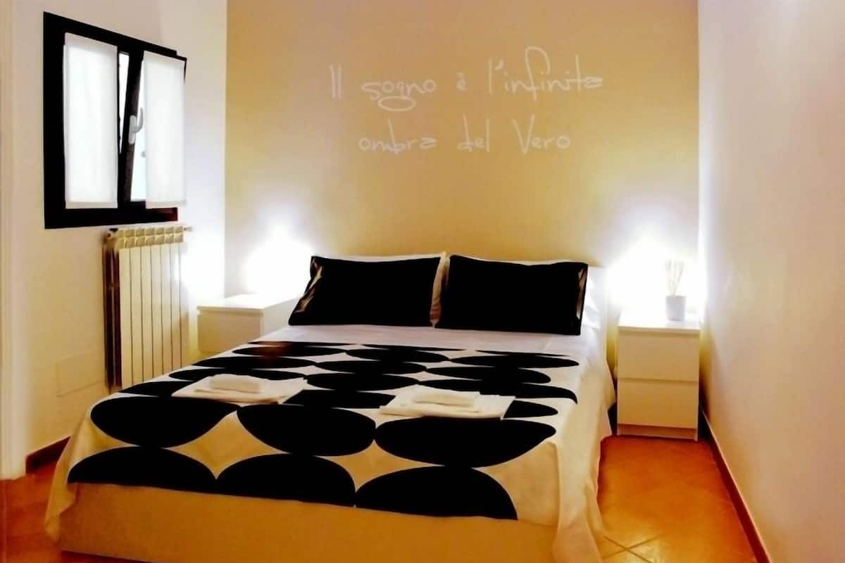 A bedroom with a bed, a radiator, a window, and a wall with a message.