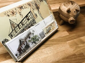 A book with a map and a piggy bank on a wooden surface. - Brunnenhof Randersacker - Das Kleine Hotel (Randersacker)