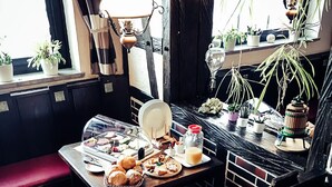 Een gezellig eetgedeelte met een gedekte tafel, een bank en diverse planten en decoraties.