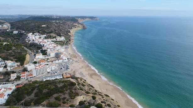 An aerial view of a coastal town with a beach, buildings, and a clear view of the sea. - Casa da Ermida near the beach and golf course (Budens)