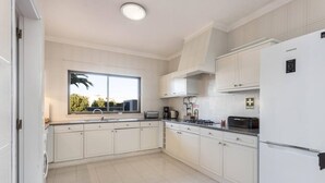 A modern kitchen with white cabinets, a large window, and a Samsung refrigerator. - Casa da Ermida near the beach and golf course (Budens)