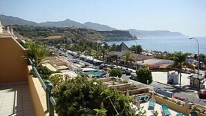 A coastal hotel with a pool area, a view of the sea, and a parking lot. - Nerja Bahía Apartamentos (Nerja)