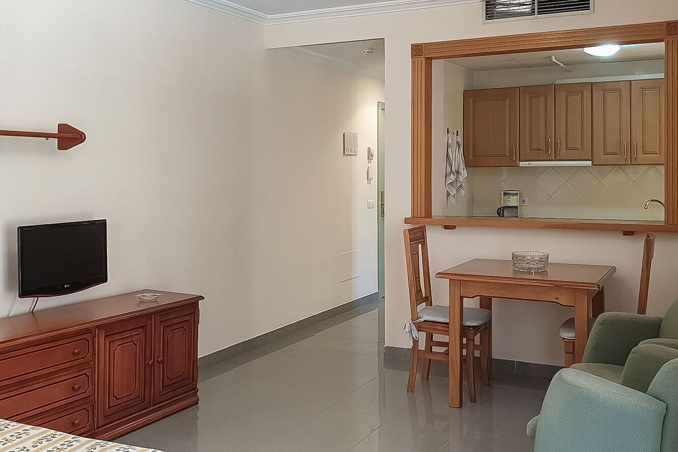 Sala de estar com televisão, armário de madeira, mesa de jantar e cadeiras.