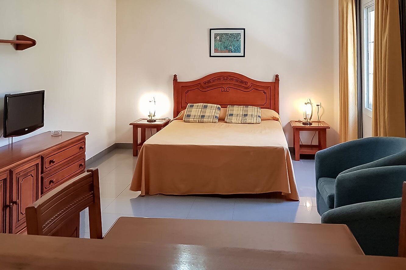 Une chambre d’hôtel comprenant un lit, des tables de chevet, une télévision, un bureau et une chaise.