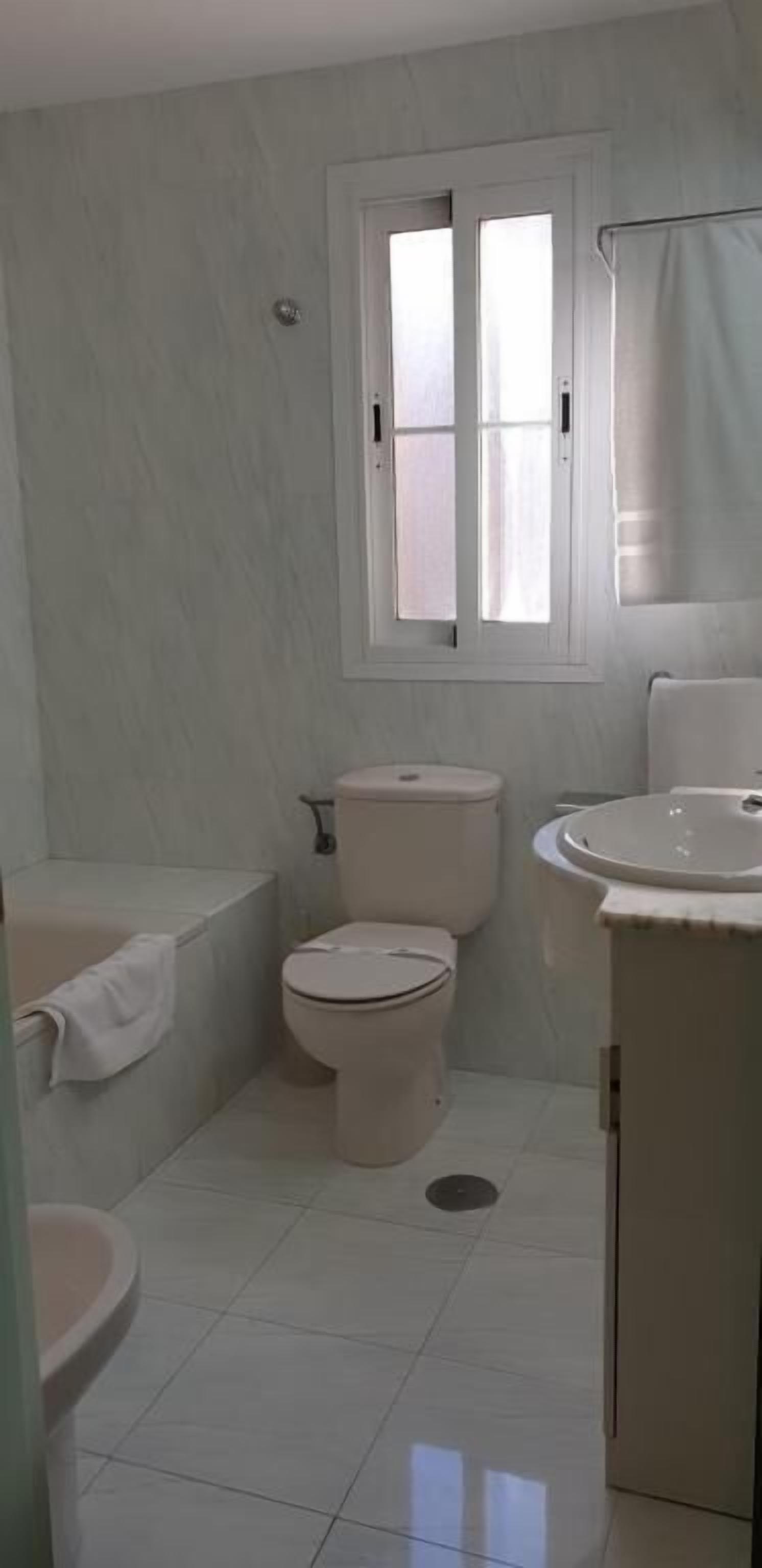 Un baño pequeño y limpio con inodoro, lavamanos y bañera.