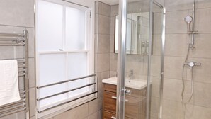 Un baño moderno con cabina de ducha de vidrio, un lavabo blanco y un perchero para toallas.