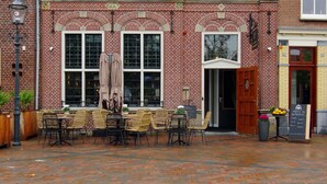 A brick building with a traditional design, featuring multiple windows and a door. - Hotel Restaurant Inn Naeldwyk (Naaldwijk)