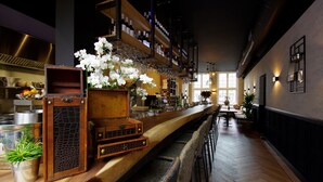 A bar area with a long counter, shelves with bottles, and chairs. - Hotel Restaurant Inn Naeldwyk (Naaldwijk)