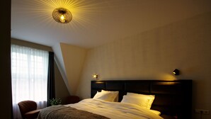 A hotel room with a large bed, a chair, a desk, and a window with curtains. - Hotel Restaurant Inn Naeldwyk (Naaldwijk)