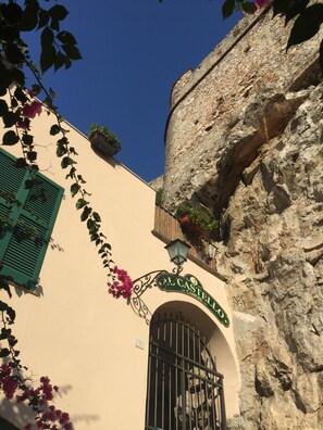 A building with a stone facade, a green shuttered window, and a sign reading "Al Castello".