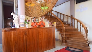 Un comptoir d’accueil avec deux employés, un escalier en bois et un plafond décoratif orné de parapluies suspendus.