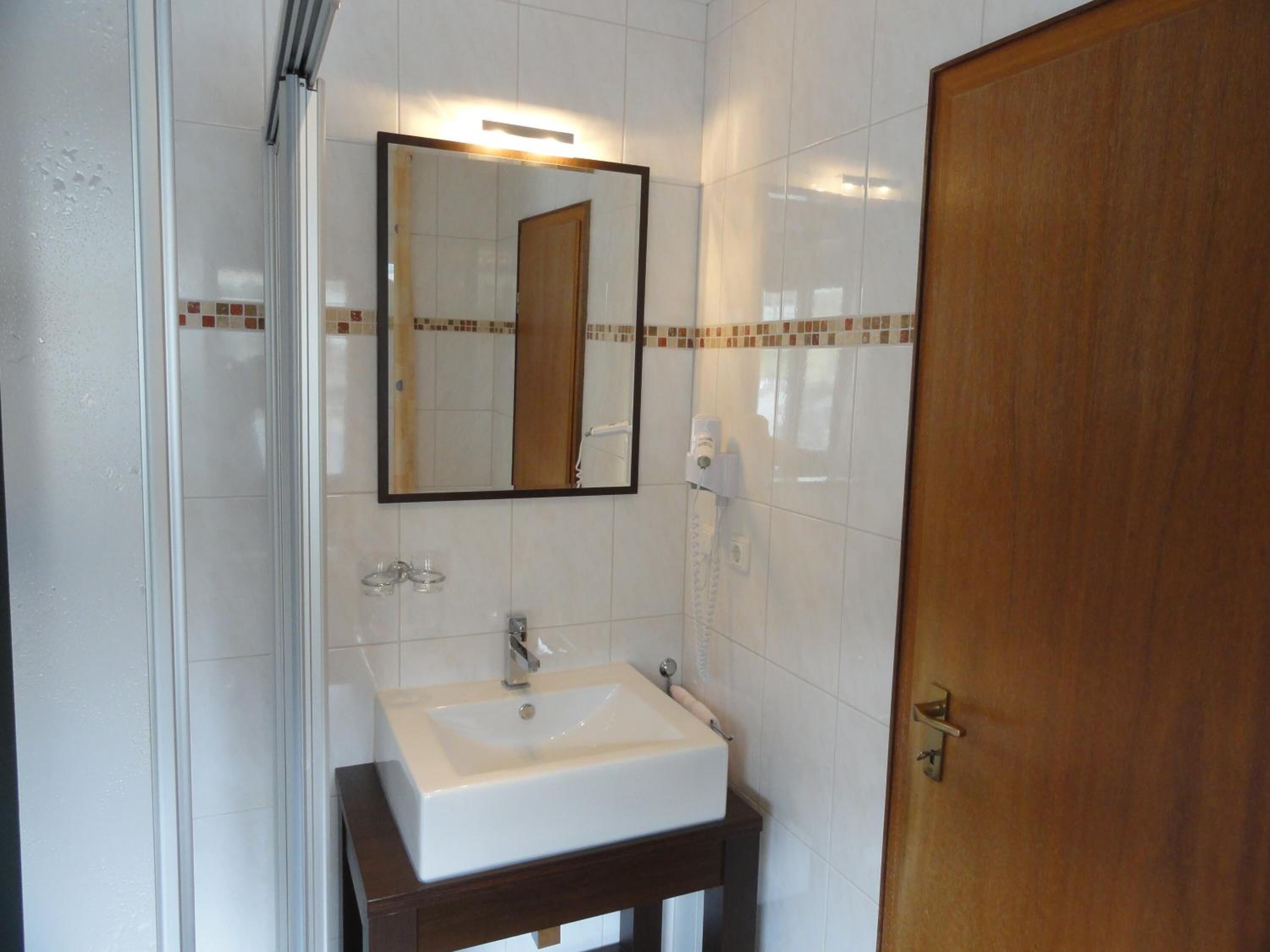 A bathroom with a white sink, a mirror, and a shower.