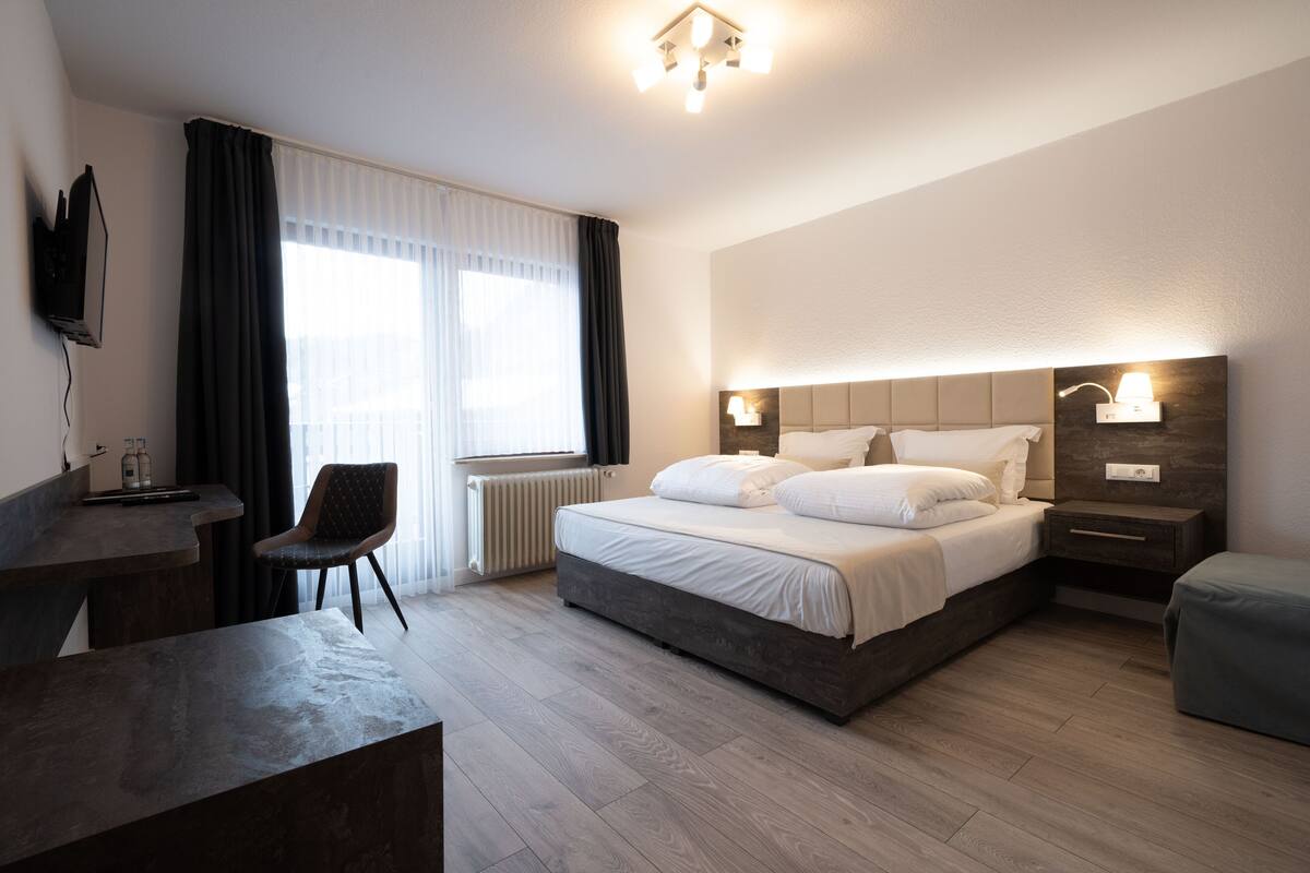 Une chambre d’hôtel moderne, dotée d’un grand lit, d’un bureau et d’une chaise.