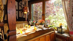 A cozy room with a wooden bench, a window with a view of trees, and a hanging lantern. - Landgasthof Göbel (Willingen)