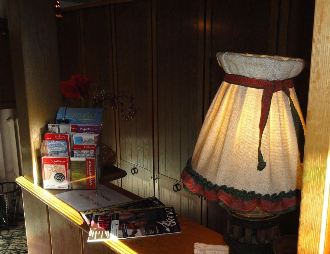 Un tavolo in legno con una lampada, un libro e alcune brochure.