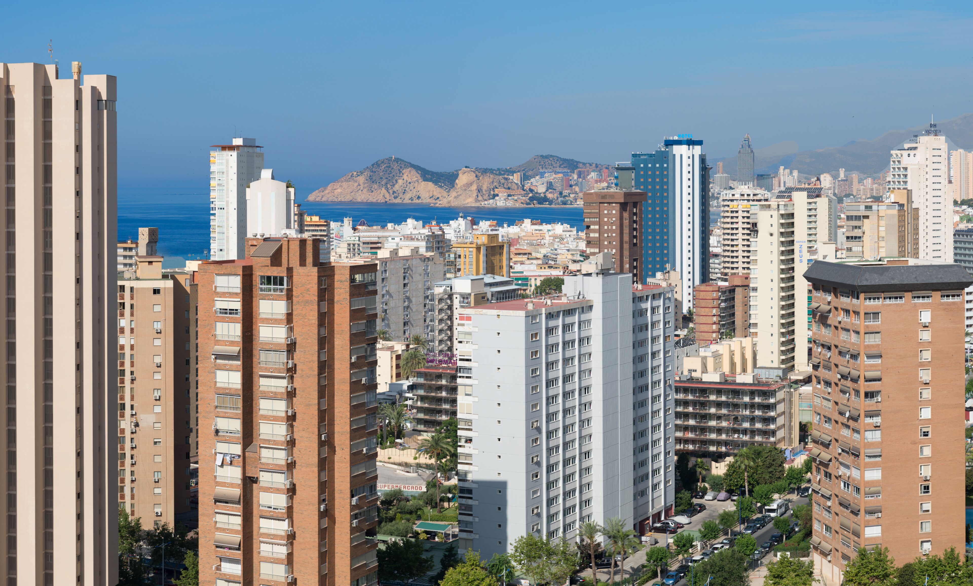 Un edificio alto con varios pisos, balcones y vista al mar.
