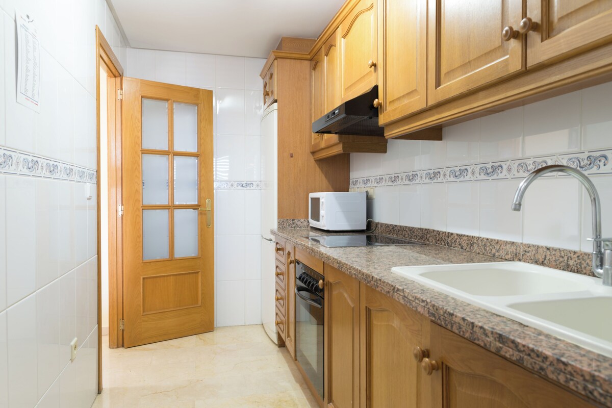 A kitchen with wooden cabinets, a microwave, a sink, and a dishwasher.