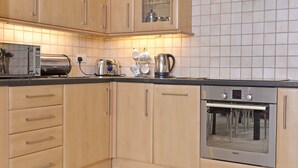 A kitchen with wooden cabinets, a toaster, a kettle, and a Bosch oven. - Cavendish Apartment (Eastbourne)