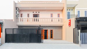 Un edificio de dos pisos con balcón, entrada protegida por una reja y fachada de azulejos.