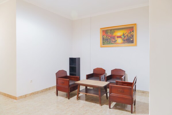 Une pièce avec une table en bois et quatre chaises, un tableau au mur et un meuble noir.