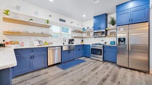 Une cuisine moderne avec des meubles bleus, des appareils en acier inoxydable et un plancher en bois.