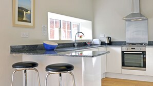 Een moderne keuken met een groot eiland, roestvrijstalen apparatuur en een raam met uitzicht op gebouwen van baksteen.