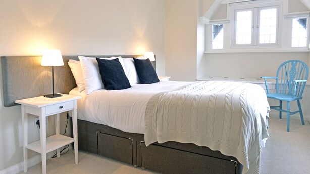 Een slaapkamer met een bed, nachtkastjes, een stoel en een raam.