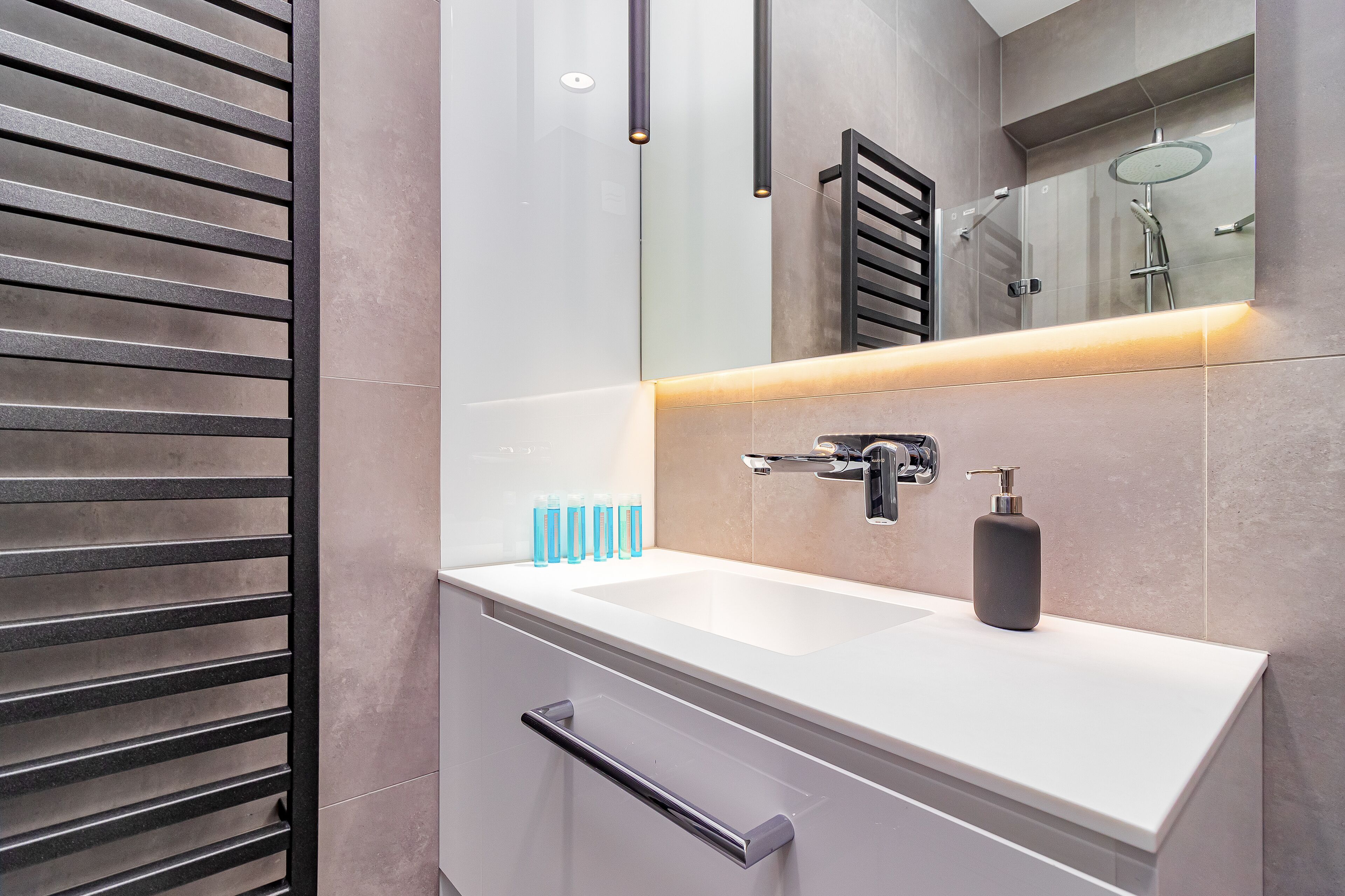 A modern bathroom with a white sink, a mirror, and a shower.